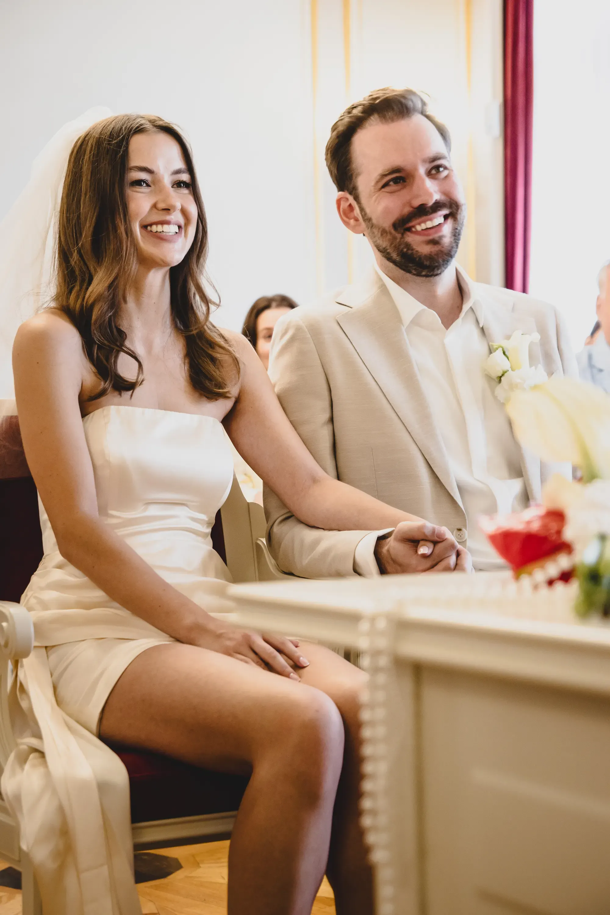 Braut und Bräutigam lachen während der Trauung und halten Händchen – Hochzeitsbilder aus Markkleeberg