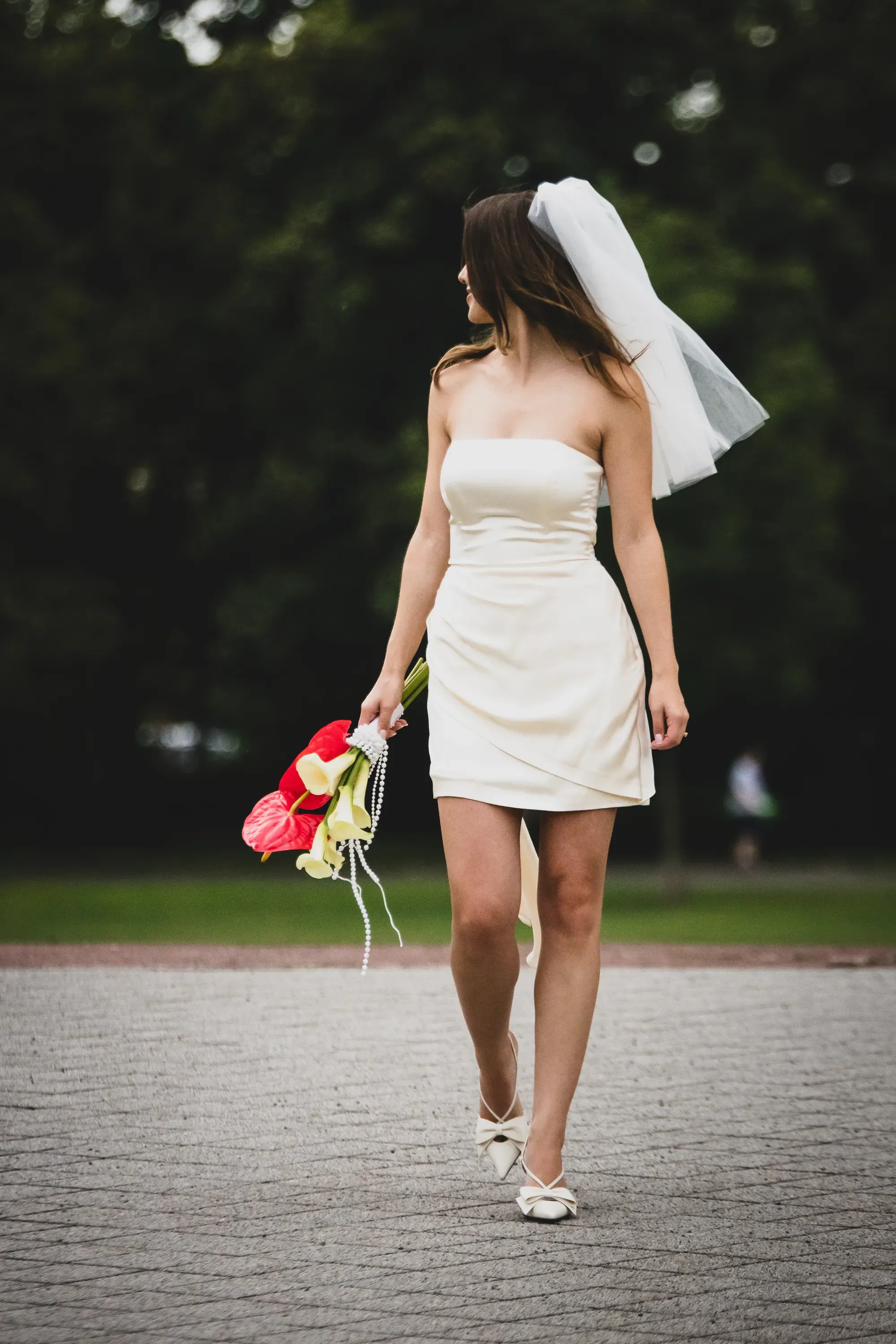 Braut allein im Gehen, Schleier und Calla-Strauß von hinten – Hochzeitsfoto