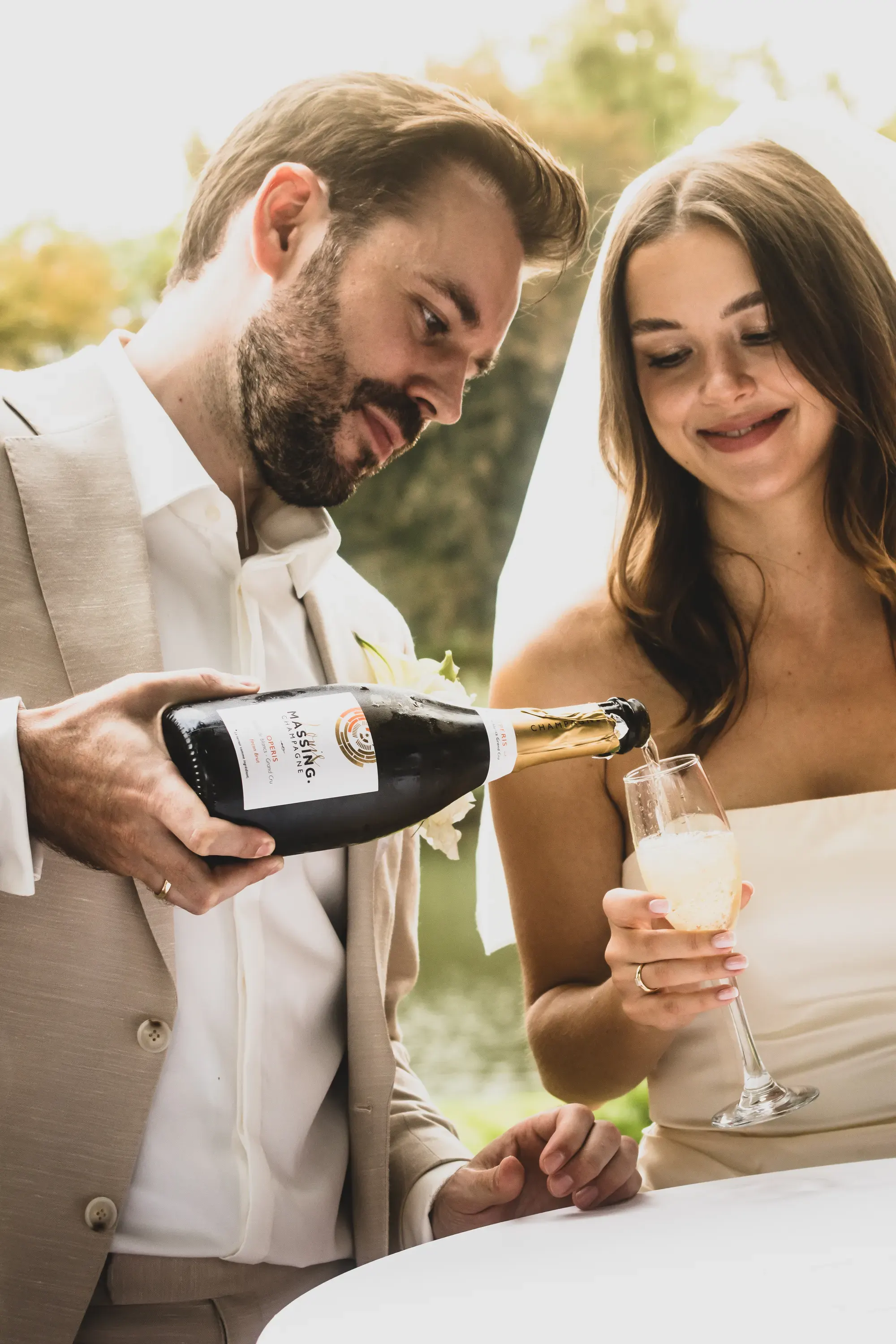 Bräutigam schenkt der Braut beim Empfang Sekt ein – Hochzeitsfoto