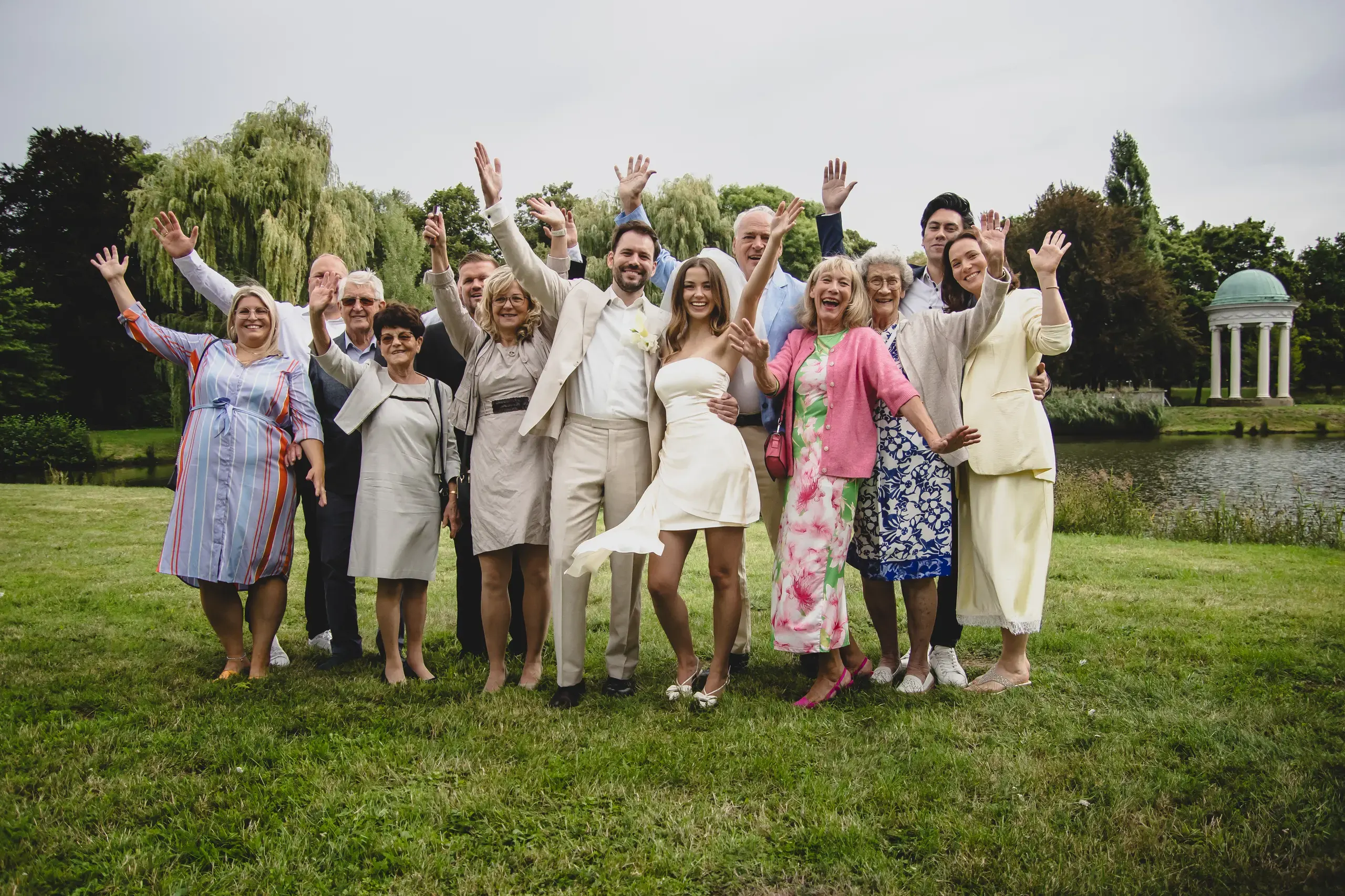 Jubelndes Gruppenbild der Hochzeitsgesellschaft auf der Wiese am Pavillon – Hochzeitsfotos